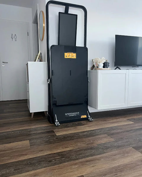 Un Gym Monster replié à la verticale dans un salon, près d’un meuble TV