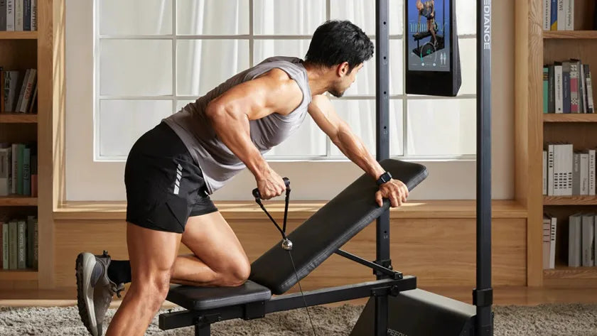 E Mann trainéiert op Gym Monster 3 doheem, an engem hellen, mat Bicher gefëllten Salon