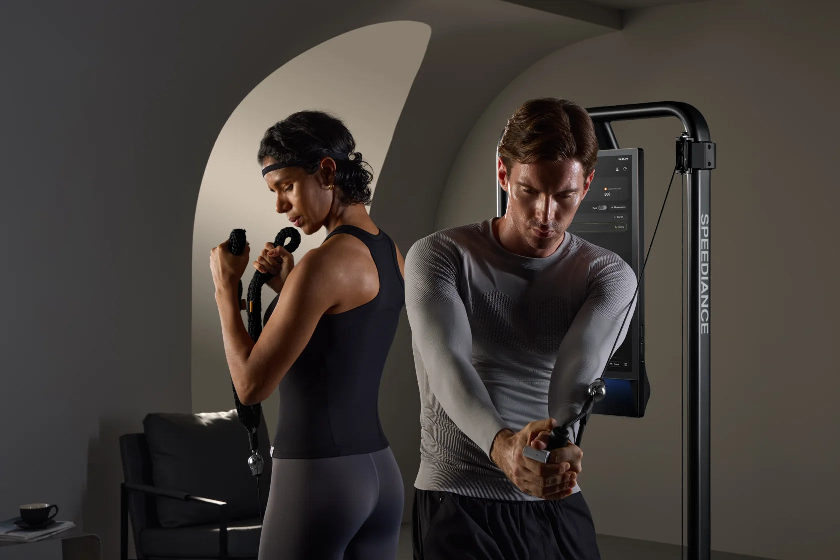 To voksne træner side om side på Gym Monster 3 i en hjemlig ramme